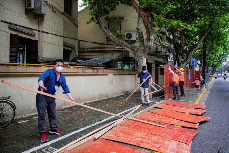 Workers dismantle barriers at a residential area during lockdown in Shanghai