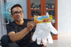 Iskandar holds up a set of plastic gloves, which used to be produced at the Chernihiv factory where he worked