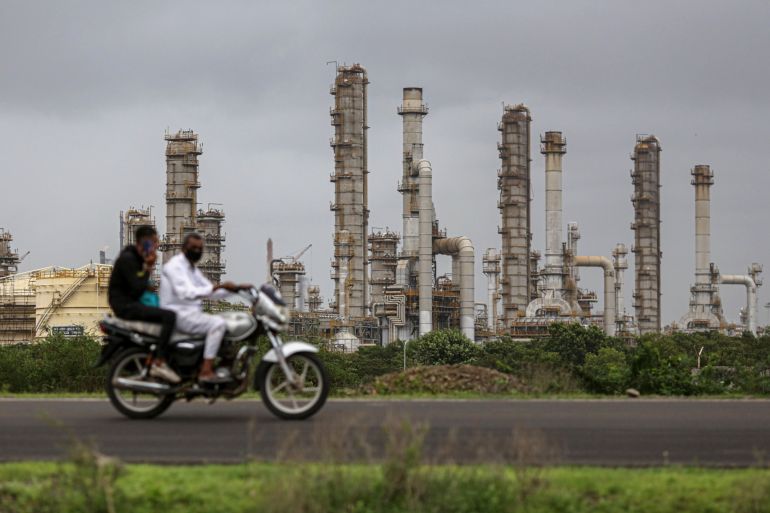 A motorcyclist drives past the Reliance Industries Ltd. oil refinery in Jamnagar, Gujarat, India