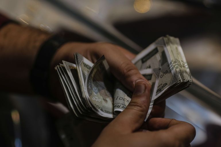A customer counts Indian rupee banknotes in Mumbai, India