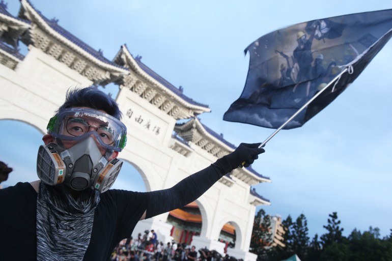 A Hong Kong protester in Taiwan holds a flag to mark the first anniversary of a mass rally in Hong Kong against its now-withdrawn extradition bill at Democracy Square in in Taipei, Taiwan, Saturday, June 13, 2020. (AP Photo/Chiang Ying-ying)