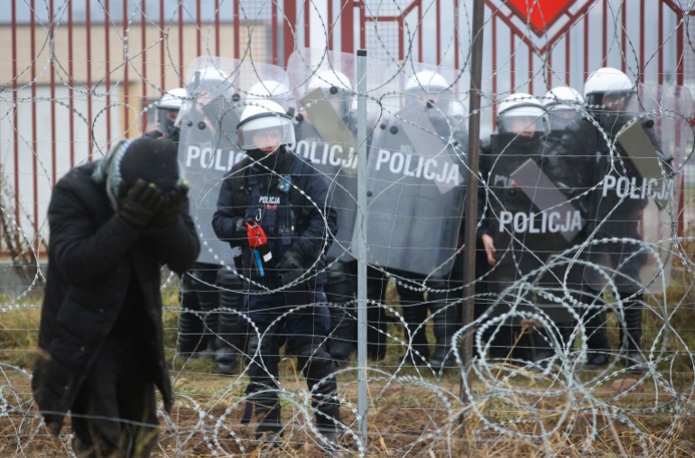 Police servicemen spray tear gas during clashes with refugees and migrants