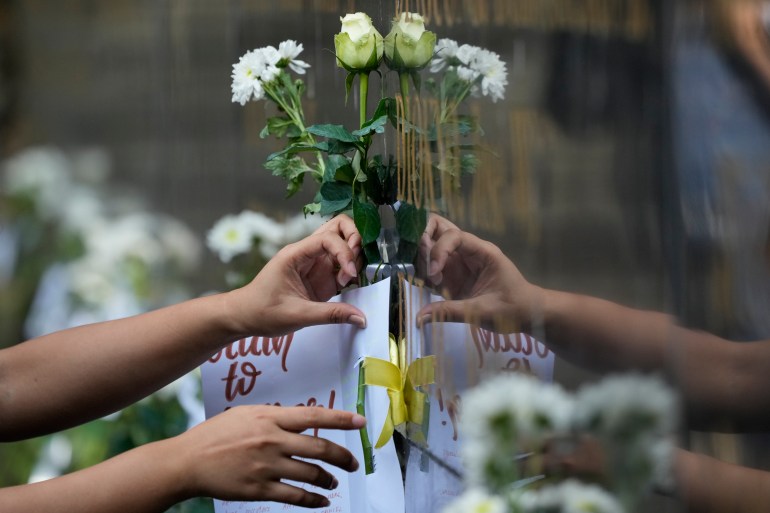 A close up of a woman placing white flowers at the memorial for those who died in the Philippines martial law era