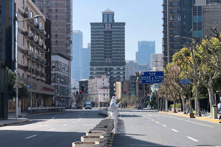 A worker in protective overalls stands in the middle of empty streets in a locked down area in the Jingan district of western Shanghai in April 2022