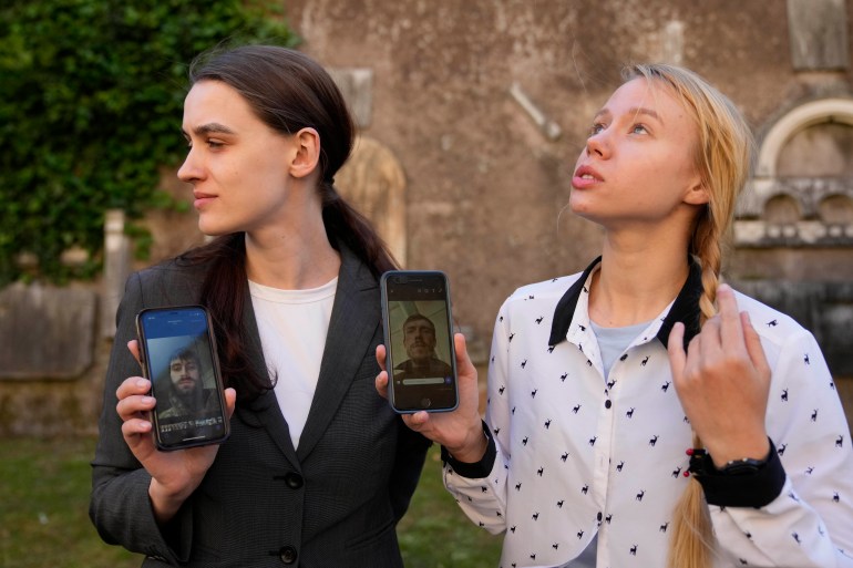 Kateryna Prokopenko, wife of Denys Prokopenko, commander of the Azov regiment, right, and Yulia Fedosiuk, wife of Arseny Fedosiuk, another member of Azov regiment get emotional as they show photos of their husbands on their phones during an interview with the Associated Press in Rome,