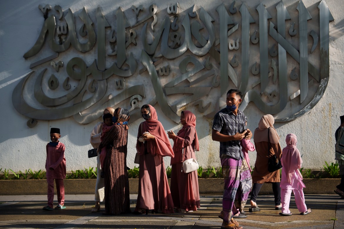 Muslims wearing protective masks stand outside the National Mosque after prayer for the Eid al-Fitr, marking the end the holy fasting month of Ramadan, in Kuala Lumpur