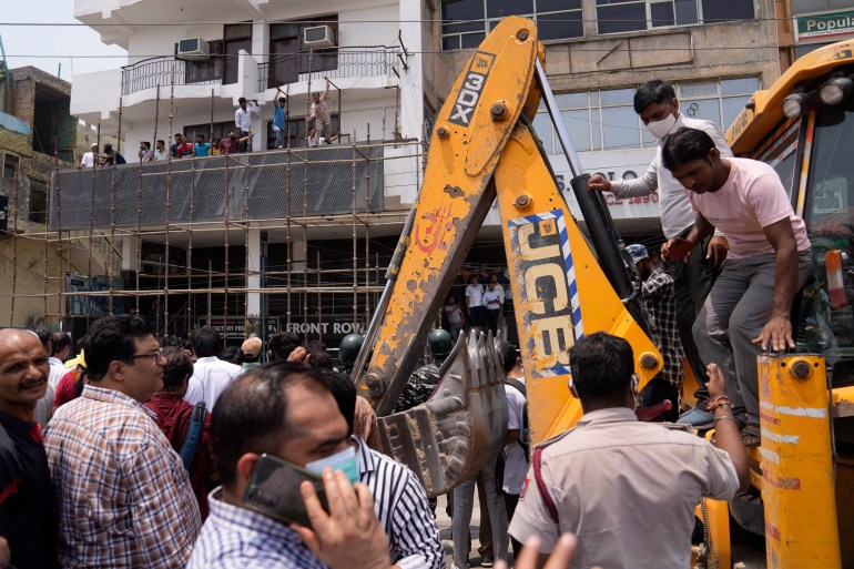 Residents and officials crowd around a bulldozer during a demolition drive in New Delhi