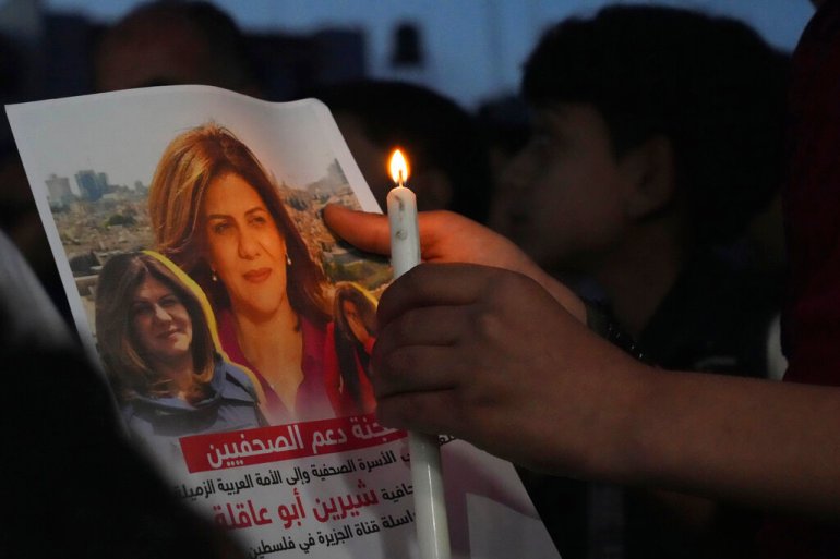Palestinian holds a candle and a picture of slain Shireen Abu Akleh