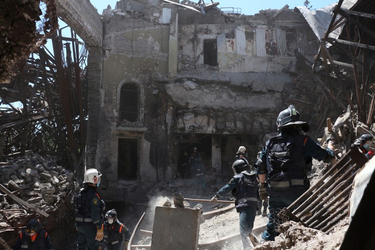 Emergency Situations Ministry employees clear rubble at the site of the damaged Mariupol theatre building