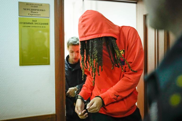 WNBA star Brittney Griner attends a court hearing in Moscow in handcuffs and with a red hoodie over her head