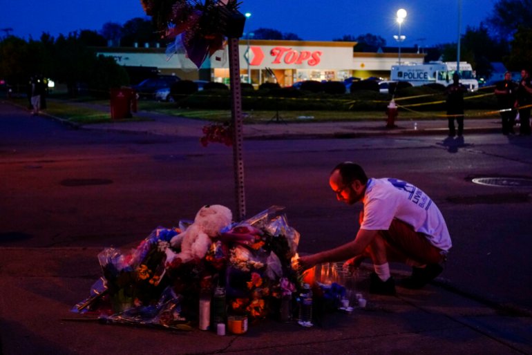 Una persona presenta sus respetos fuera de la escena de un tiroteo en un supermercado, en Buffalo, NY