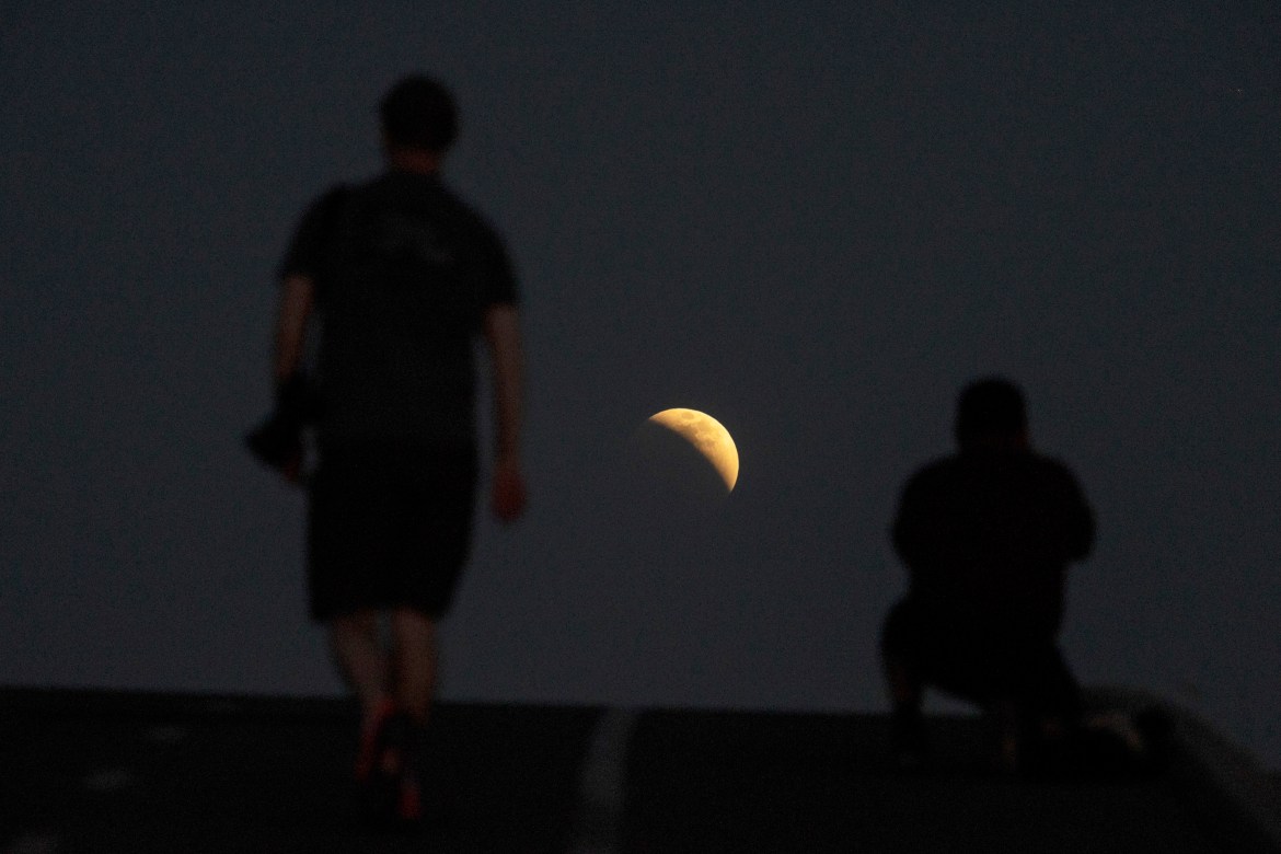 People take photos of a a lunar eclipse during the first blood moon of the year, in Irwindale