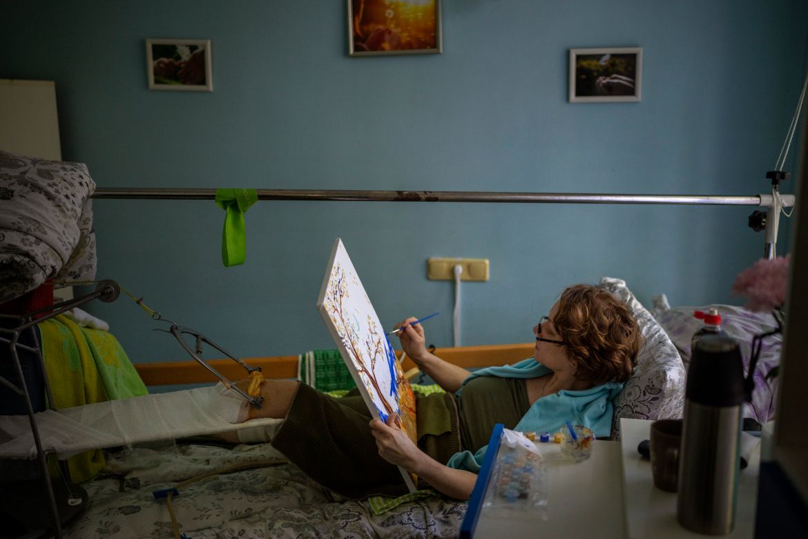 Olena Viter, 45, paints on her bed as she recovers from her wounds at a public hospital in Kyiv