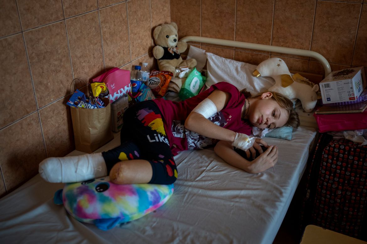 Yana Stepanenko, 11, looks at her phone as she lies in bed at a public hospital in Lviv