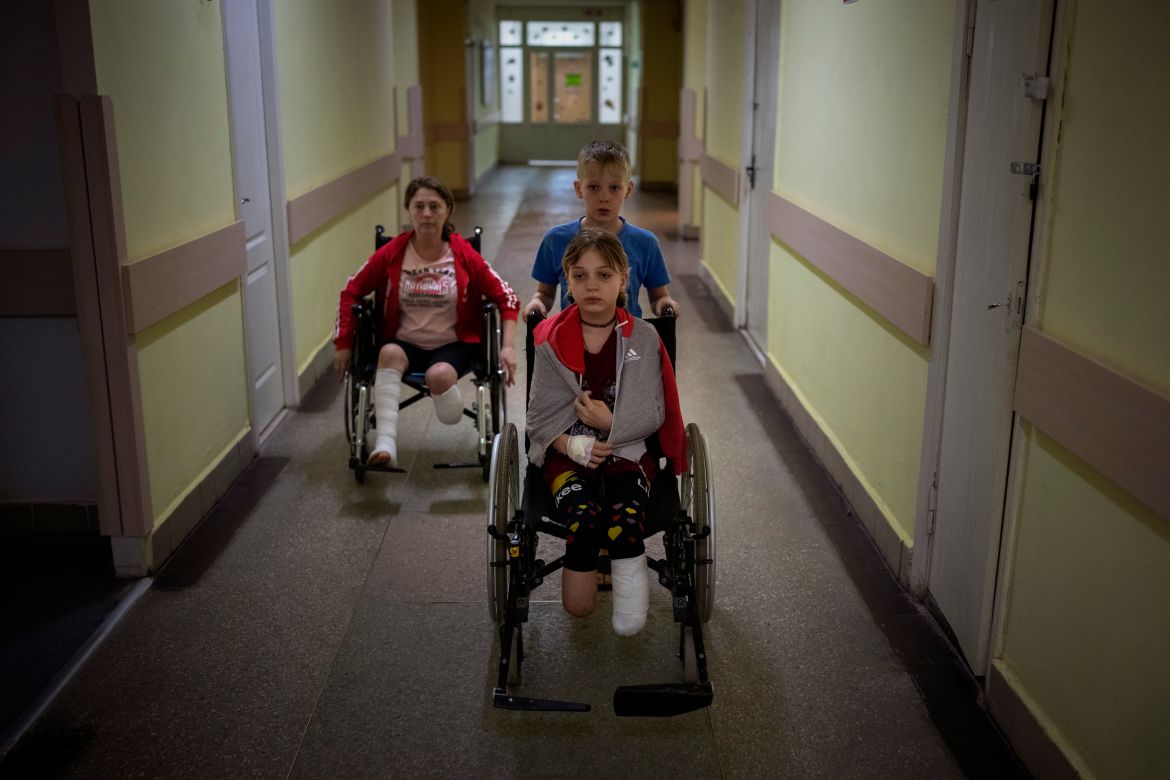 Followed by their mother Natasha, Yarik Stepanenko, 11, pushes his twin sister Yana's wheelchair along a corridor of a public hospital in Lviv,
