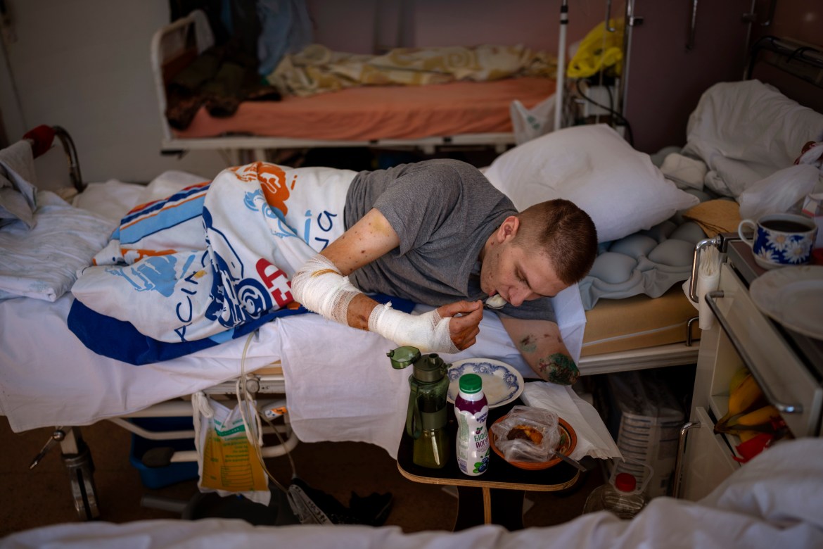 Anton Gladun, 22, eats on his bed in at the Third City Hospital, in Cherkasy