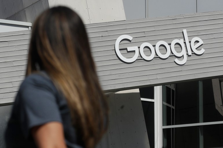 A woman walks below a Google sign on the campus in Mountain View, California