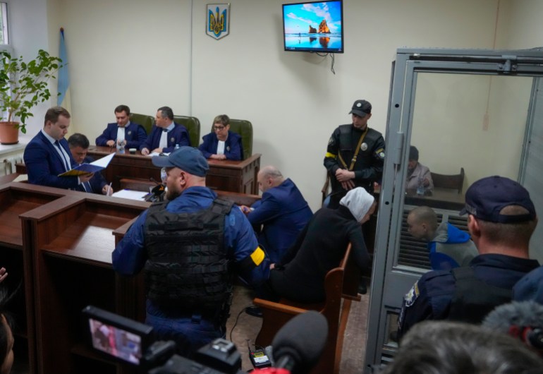 Sitting behind a glass, Russian army Sergeant Vadim Shishimarin, 21, talks with his translator, centre right, during a court hearing in Kyiv, Ukraine,