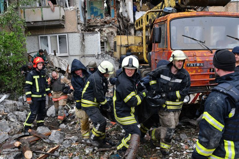 Rescuers carry the body of a civilian at a site of an apartment building