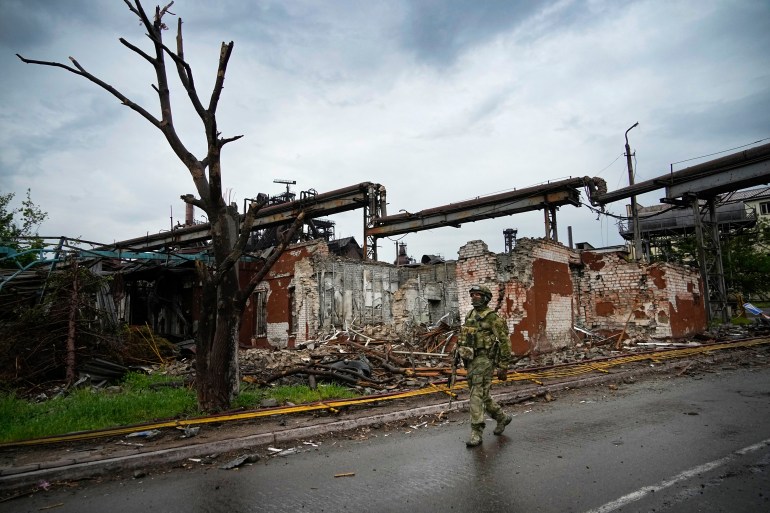 A Russian soldier patrols a destroyed part of an ironworks plant in Mariupol