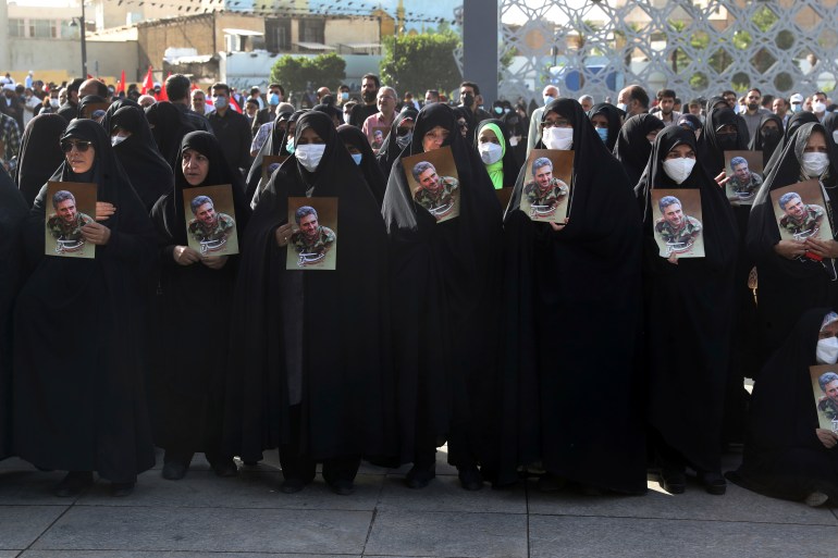 Mourners hold posters of Iran's Revolutionary Guard Col. Hassan Sayyad Khodaei during his funeral ceremony
