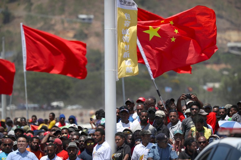 Spectators hold a Chinese flag as they watch a ceremony.
