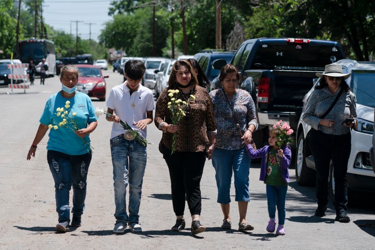 Victims' parents and relatives walking with flowers in hand.