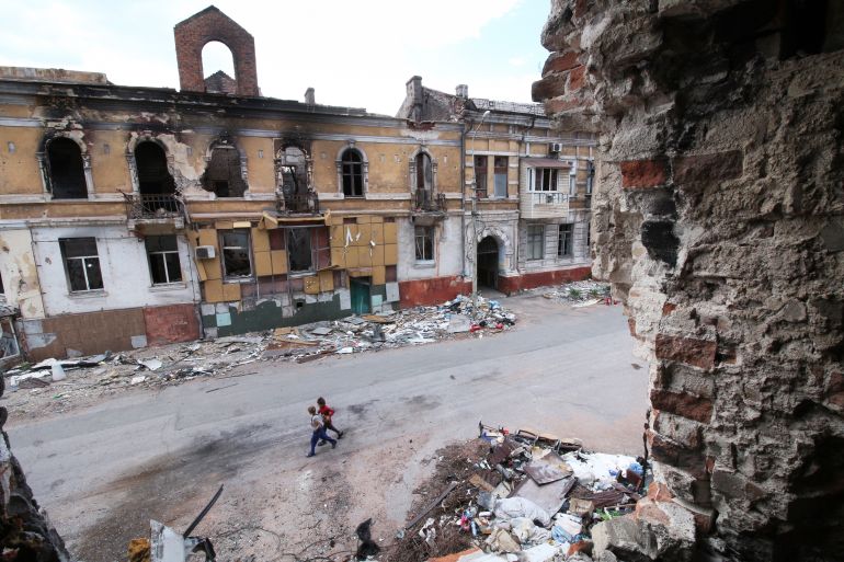 Children walk among buildings destroyed