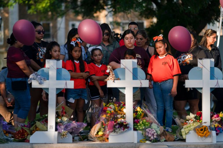 People gather at a memorial site to pay their respects for the victims killed in this week's elementary school shooting in Uvalde, Texas.