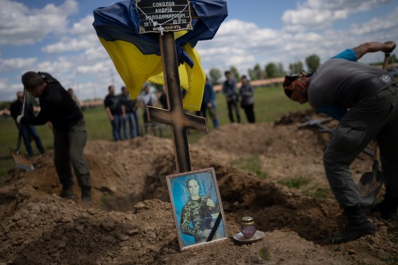 A Ukrainian soldier is buried in eastern Ukraine with the country's blue and yellow flag fluttering around the cross bearing his name