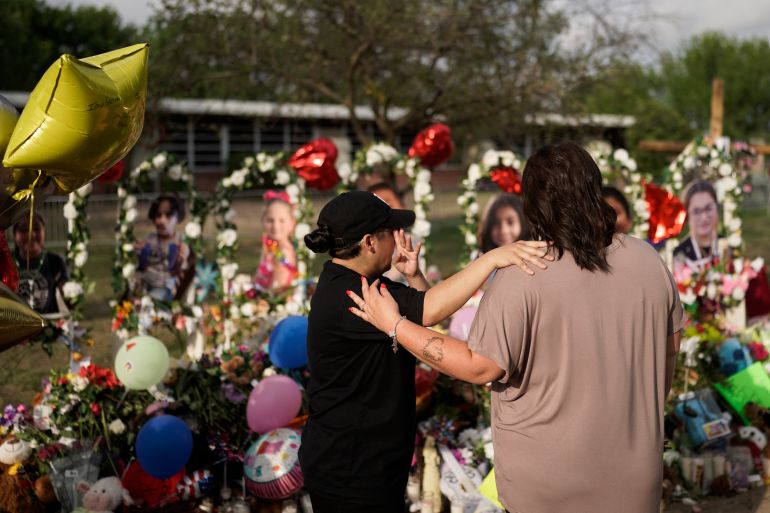 Women hug in front of a memorial in Uvalde, Texas