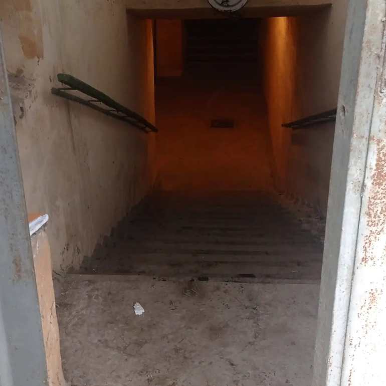 Los escalones que conducen al complejo subterráneo con un pasamanos iluminado en un lado y una luz en la parte inferior