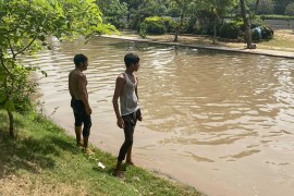 Two men stand next to a canal in the Pakistani city of Lahore after taking a dip to cool off [Usaid Siddiqui/Al Jazeera]
