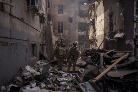 Ukrainian service members walk among debris of damaged buildings after a Russian attack in Kharkiv, Ukraine [File: Felipe Dana/AP]