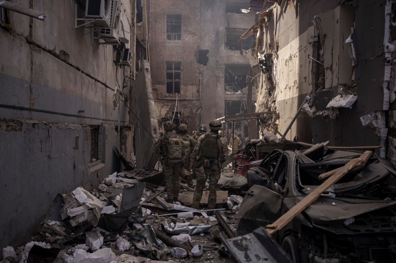 Ukrainian service members walk among debris of damaged buildings after a Russian attack in Kharkiv, Ukraine.