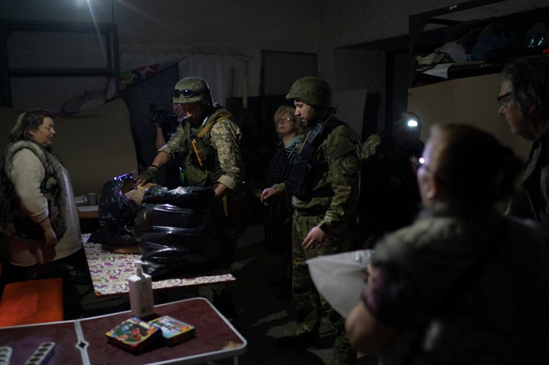 Policemen deliver bags of breads to people living inside a basement used as a bomb shelter in Severodonetsk, Ukraine.
