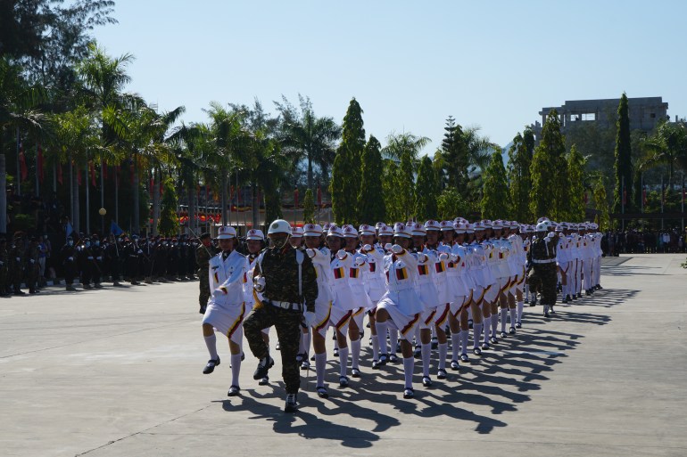 Female soldiers in white uniform march in formation at the presidential palace to mark 20 years of Timorese independence