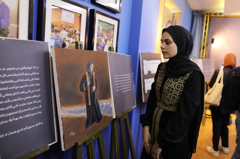 Zainab looks to one of her paintings.