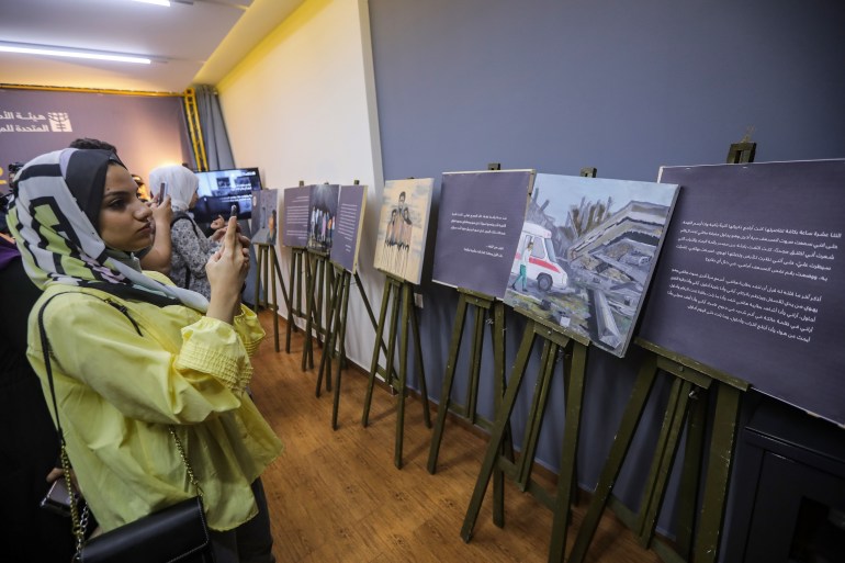 Visitors take photos of Zainab's paintings.