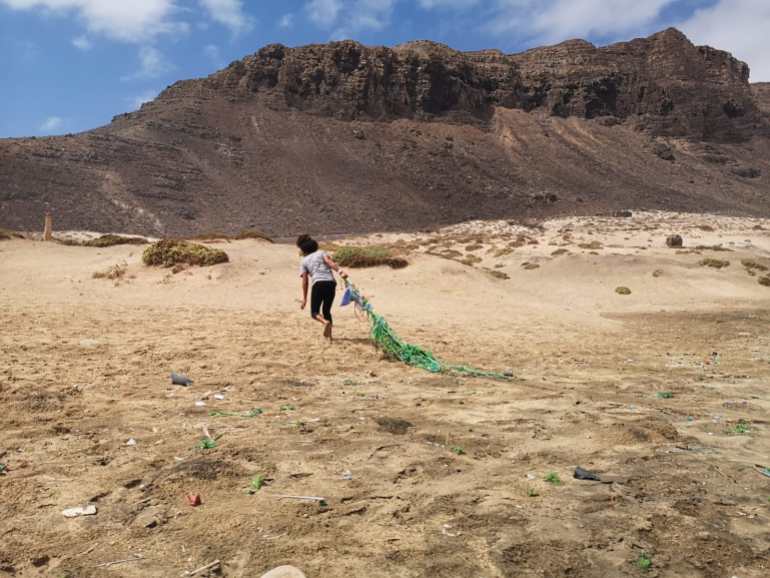 A woman drags a "ghost net" off the beach on the island of São Vincente, Cape Verde