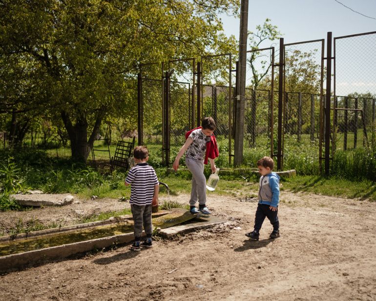 Three children standing in front of a fence.