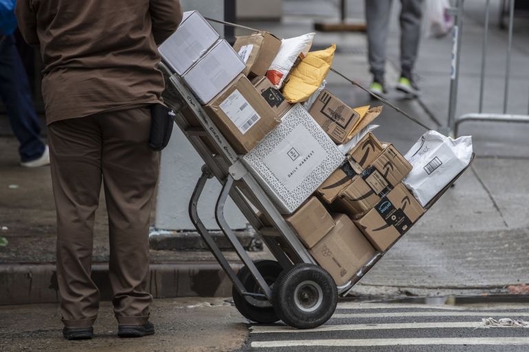 A United Parcel Service Inc. (UPS) driver pushes a trolley with Amazon boxes during a delivery in New York, U.S.
