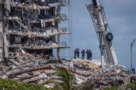 Members of the South Florida Urban Search and Rescue team look for possible survivors in the partially collapsed 12-story Champlain Towers South condo building on June 27, 2021 in Surfside, Florida