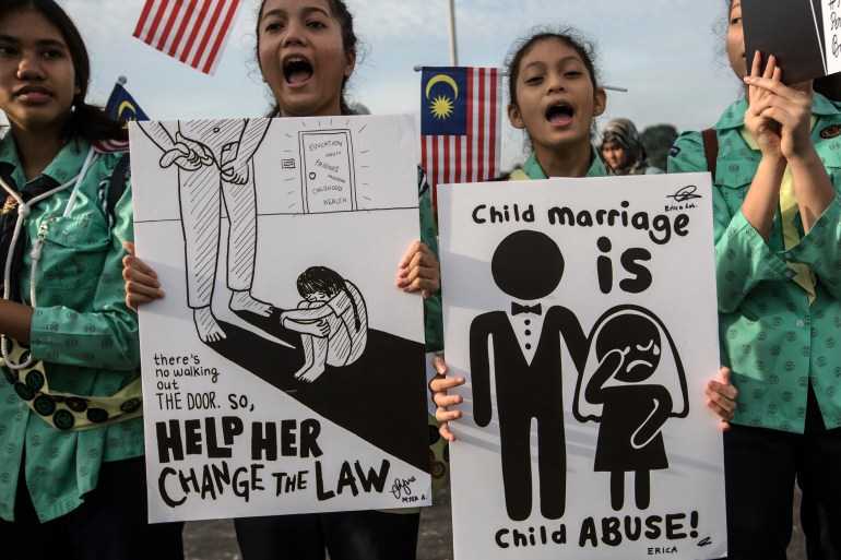 Young women gather outside Malaysia's parliament with banners calling for an end to child marriage. One placard showing a stick man marrying a young girl says 'child marriage is child abuse'