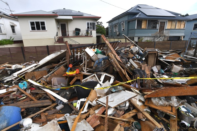 Глыбы разрушенной мебели, одежды и других личных вещей, сложенные на улице возле домов, пострадавших от наводнения в Лисморе.