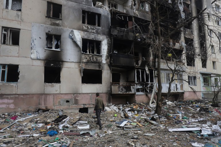 A man walks past a residential building damaged during a shelling in Severodonetsk