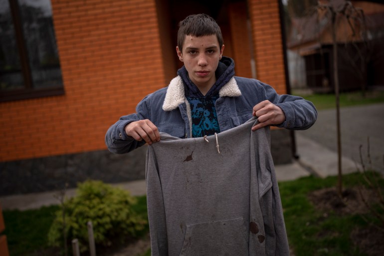 Yura Nechyporenko, 15, holds the hoodie he was wearing the day a Russian soldier tried to kill him in Bucha, on the outskirts of Kyiv, Ukraine, on Tuesday, April 19, 2022