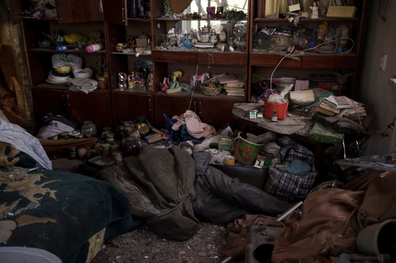 O corpo de um civil está em um apartamento enquanto os bombardeios russos continuam em uma vila recentemente retomada pelas forças ucranianas perto de Kharkiv.
