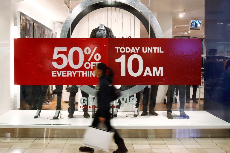 A woman walks by a store's discount advertisement inside the Roosevelt Field Mall in Garden City, New York
