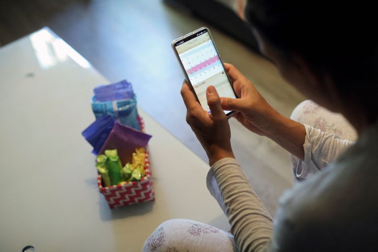 Raquel del Rio, 36, who works in police forces, poses as she observes a period calendar tracker app on her mobile phone at her home in Madrid, Spain